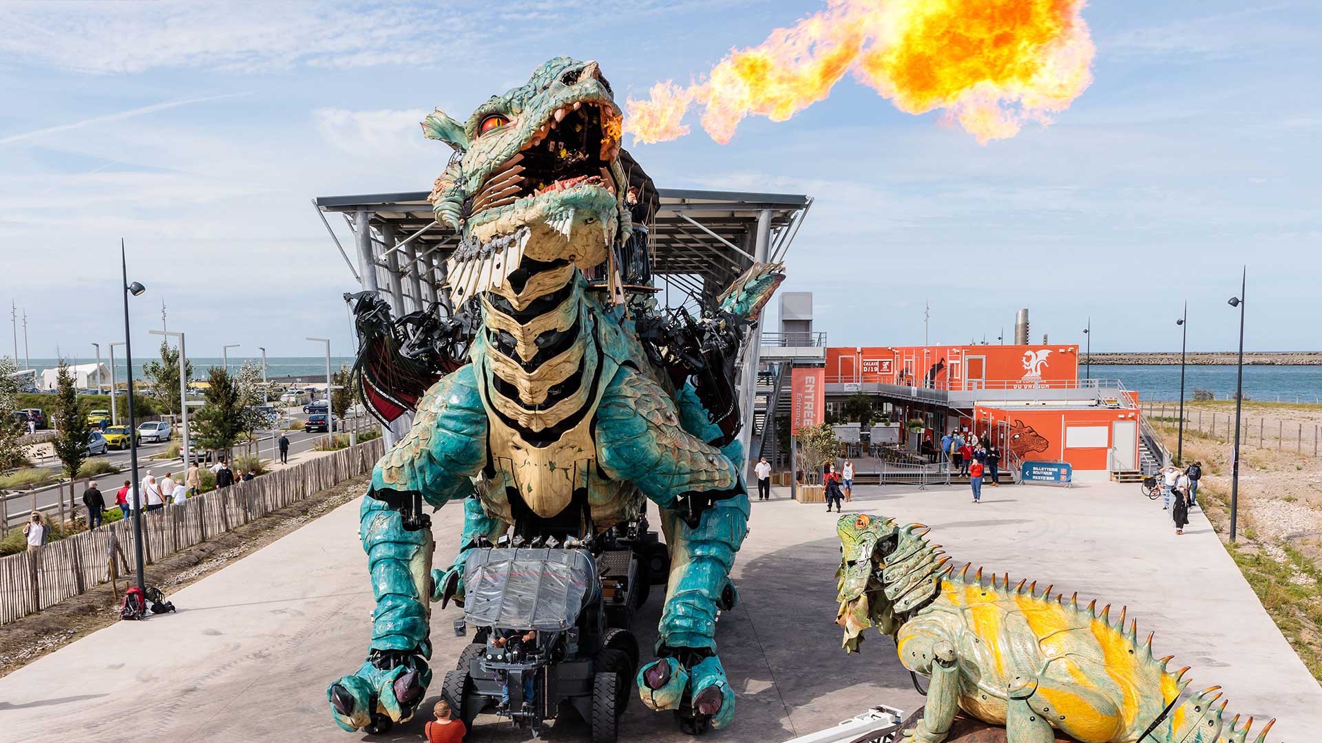 Vue du Dragon de Calais crachant des flammes face à l'Iguane Sentinelle, sur le parvis de la Cité du Dragon à Calais