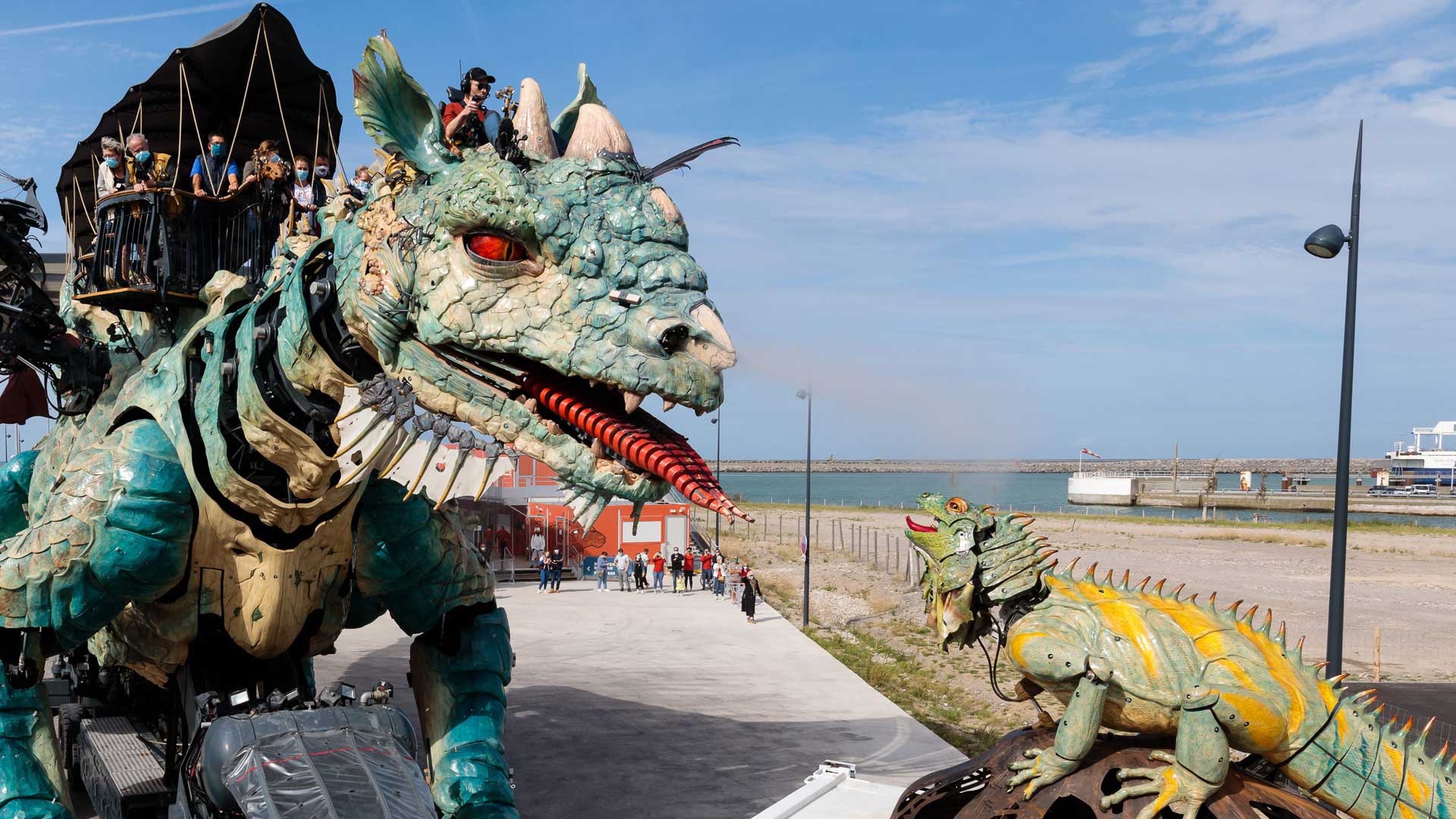Rencontre théâtrale entre le Dragon de Calais et l'Iguane Sentinelle sur le parvis de la Cité du Dragon à Calais